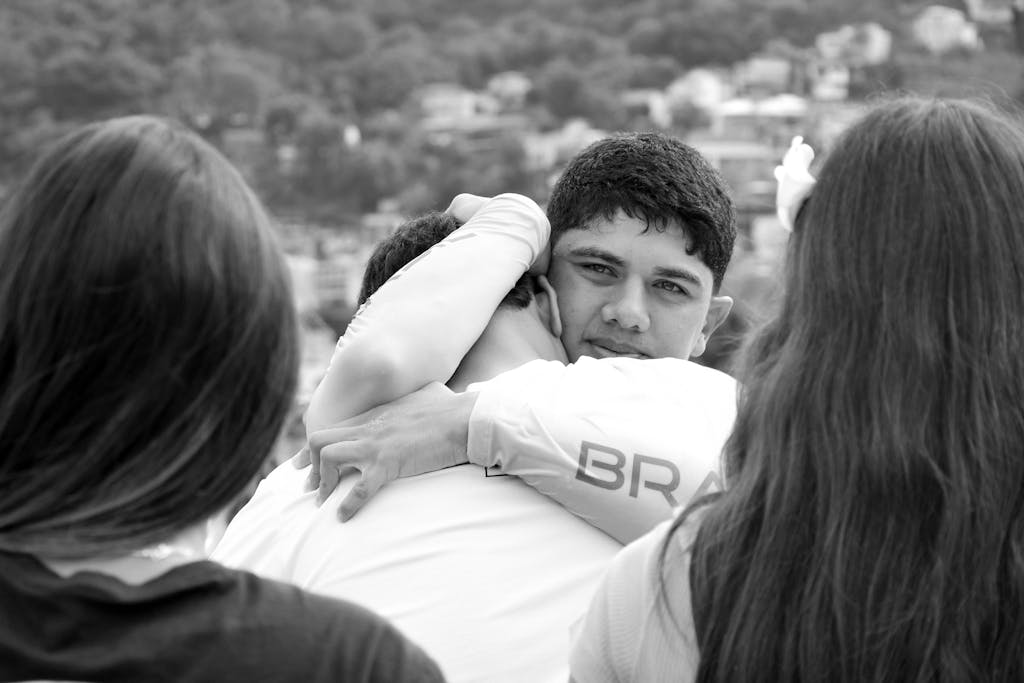 A heartfelt embrace between friends with a view of Rio de Janeiro in the background.