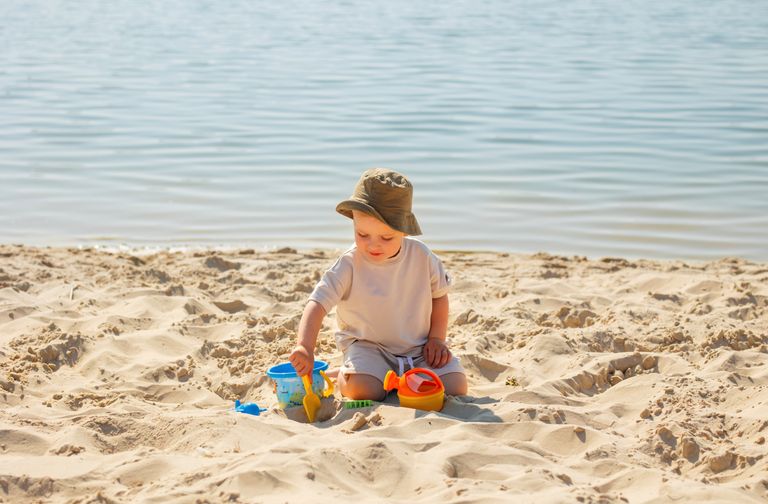A young boy enjoying a sunny day at the beach, playing with toys in the sand.